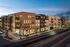 Modern apartment complex with warm brick facade and vibrant retail spaces, beautifully lit during twilight in an urban setting.