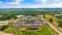 Aerial view of modern apartment complex surrounded by lush greenery and scenic hills, featuring a central courtyard and ample parking space.