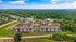 Breathtaking aerial view of a luxurious apartment complex surrounded by lush greenery and expansive landscapes, featuring modern buildings and resort-style amenities.