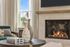 Elegant living room with a modern fireplace, tasteful decor on a round table, and a large window offering a serene view.