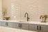 Elegant kitchen space featuring a glossy geometric backsplash, sleek black faucet, and artistic decor for modern style.