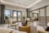 Inviting apartment lounge featuring modern armchairs, a stylish round coffee table, and an elegant sliding glass door leading to a bright, airy room with plush seating.