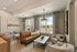Bright and inviting lounge area featuring contemporary decor, a stylish brown sofa, modern lighting, and large windows with serene views.
