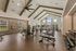 Modern apartment gym with vaulted ceilings, featuring state-of-the-art exercise equipment, spacious layout, and large windows for natural light.