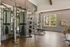 Modern apartment gym with advanced fitness equipment and large windows offering scenic views.