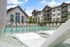 Luxurious apartment complex with a pristine outdoor pool, surrounded by elegant lounge chairs and modern architecture, perfect for relaxation and leisure.