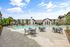 Luxurious apartment complex showcasing a sparkling outdoor pool with stylish lounge chairs and modern patio seating, perfect for relaxation.