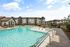 Luxurious apartment complex featuring a sparkling swimming pool with stylish lounge chairs and modern amenities.