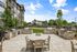 Modern apartment complex with a stylish outdoor grilling area, featuring multiple built-in grills and comfortable seating surrounded by lush greenery.