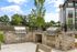 Inviting outdoor BBQ area with sleek stainless steel grills, surrounded by lush greenery and modern apartment backdrop, perfect for entertaining.