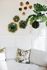 Chic living room with decorative green wall art, lush potted plant, and cozy textured sofa with floral pillows.