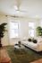 Inviting living room with natural light, featuring a cozy white sofa, elegant green rug, and vibrant plants for a serene ambiance.