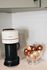 Sleek kitchen corner featuring a modern coffee machine with a chic bowl of coffee pods, set against elegant white subway tiles.