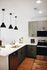 Modern kitchen with sleek black pendant lights, a stainless steel stove, and elegant green cabinetry.
