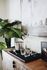 Elegant modern interior showcasing a stylish bar setup with glassware on a rustic wooden cabinet, complemented by vibrant green plants and contemporary artwork.