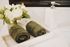 Luxurious bathroom counter featuring elegant white marble decor, neatly rolled green towels, and a stylish floral arrangement for a touch of tranquility.
