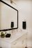 Elegant bathroom with a sleek marble countertop, large framed mirror, and stylish metal fixtures.