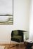 Elegant living space featuring a plush green velvet chair with modern gold legs and a contemporary landscape painting.