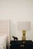 Elegant bedroom corner with plush tufted headboard, matching contemporary nightstand, artistic decor piece, and stylish table lamp.