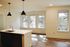 Bright modern kitchen with a sleek island and stylish pendant lighting, complemented by large windows offering a scenic tree-lined view.