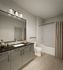 Modern bathroom featuring sleek cabinetry, elegant countertop, and luxurious lighting over a large mirror.