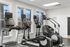 Modern fitness center with state-of-the-art Life Fitness equipment, featuring two treadmills and an elliptical, set against a bright, spacious environment with large windows.