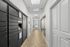 Modern apartment corridor featuring secure mailbox lockers and tiled flooring, leading to a bright exit door.