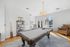 Bright and inviting recreational room featuring a stylish pool table, cozy seating, and natural light through large windows.