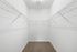 Spacious walk-in closet with bright lighting, featuring sleek wire shelving and plush carpet flooring.