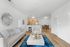 Bright open-plan living area featuring elegant seating, a plush blue rug, modern kitchen, and stylish dining space.