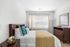 Charming bedroom with natural light, featuring elegant wood furniture, decorative pillows, and cozy ambiance.