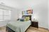 Inviting bedroom with stylish decor, featuring a cozy bed with colorful pillows, elegant nightstands, and vibrant abstract wall art, perfect for relaxation.