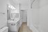 Bright, modern bathroom featuring elegant white fixtures, a sleek vanity with large mirror, and a spacious tub.