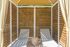 Chic outdoor cabana with modern wooden slatted walls, two comfortable lounge chairs, and cozy ambiance.