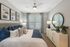 Luxurious bedroom featuring a plush bed with decorative pillows, elegant artwork, and modern furnishings, bathed in natural light.
