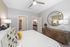 Chic bedroom featuring cozy bedding, modern ceiling fan, wooden dresser with stylish mirror, and a vibrant, welcoming atmosphere.