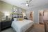 Chic bedroom with modern decor, featuring a stylish bed, abstract wall art, and ambient lighting, leading to a private ensuite and cozy hallway.