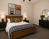 Inviting bedroom with modern decor, cozy bed, stylish artwork, and elegant lighting creating a warm ambiance.