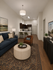 Elegant modern living room with plush seating, tasteful decor, and an open kitchen with chic pendant lighting.