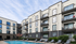 Modern apartment complex with sleek balconies overlooking a pristine swimming pool, ideal for luxurious living.