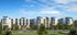 Luxurious apartment complex with modern architecture, featuring elegant balconies and surrounded by lush greenery under a clear blue sky.
