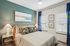 Elegant bedroom with a stylish accent wall, chic artwork, and plush bedding, complemented by soft lighting and natural light from the window.
