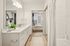 Bright and elegant bathroom with dual sinks leading to a cozy bedroom, featuring modern decor and white subway tiles.