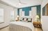Inviting bedroom with elegant decor, featuring a cozy bed, stylish bedside lamps, and a tranquil teal accent wall.
