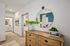 Inviting hallway with elegant wooden dresser and decorative mirror reflecting a cozy bedroom with chic decor.