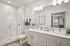 Elegant bathroom showcasing dual sinks, a glass-enclosed shower, and chic lighting fixtures, designed for comfort and style.