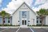 Charming clubhouse exterior with inviting entryway, palm trees, and vibrant blue sky, perfect for community gatherings.