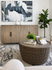 Elegant living room featuring a stylish wicker coffee table, modern abstract art, and lush greenery for a cozy ambiance.