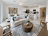 Modern open-concept living space featuring a cozy seating area, elegant dining setup, and sleek white kitchen with stylish decor.