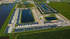 Aerial view of a modern residential development featuring stylish townhomes, scenic ponds, and lush green spaces, offering a serene and inviting community atmosphere.